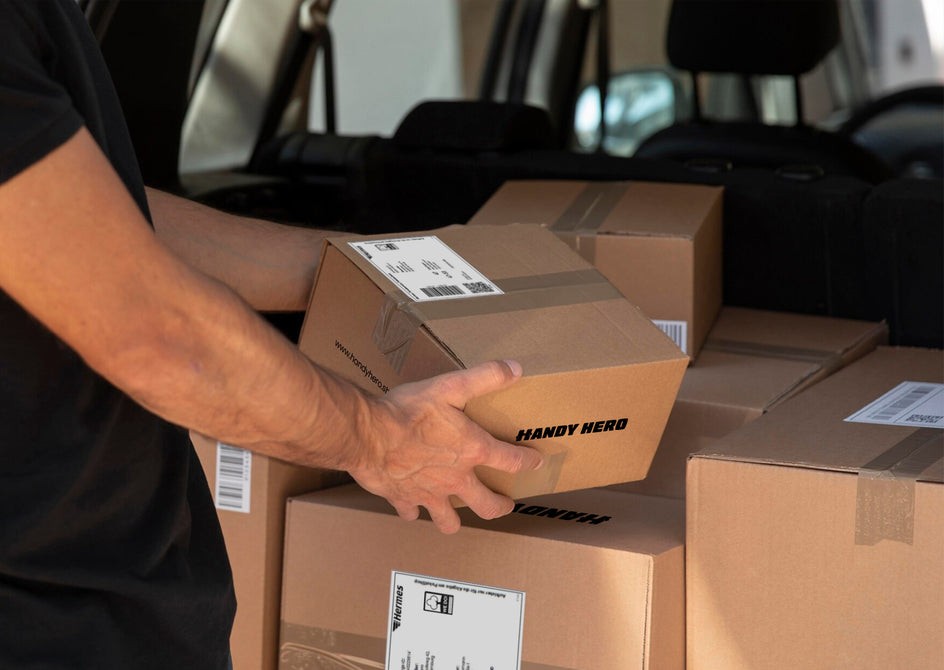 Nahaufnahme von Händen, die ein Smartphone in ein Versandpaket legen – Einsendeprozess