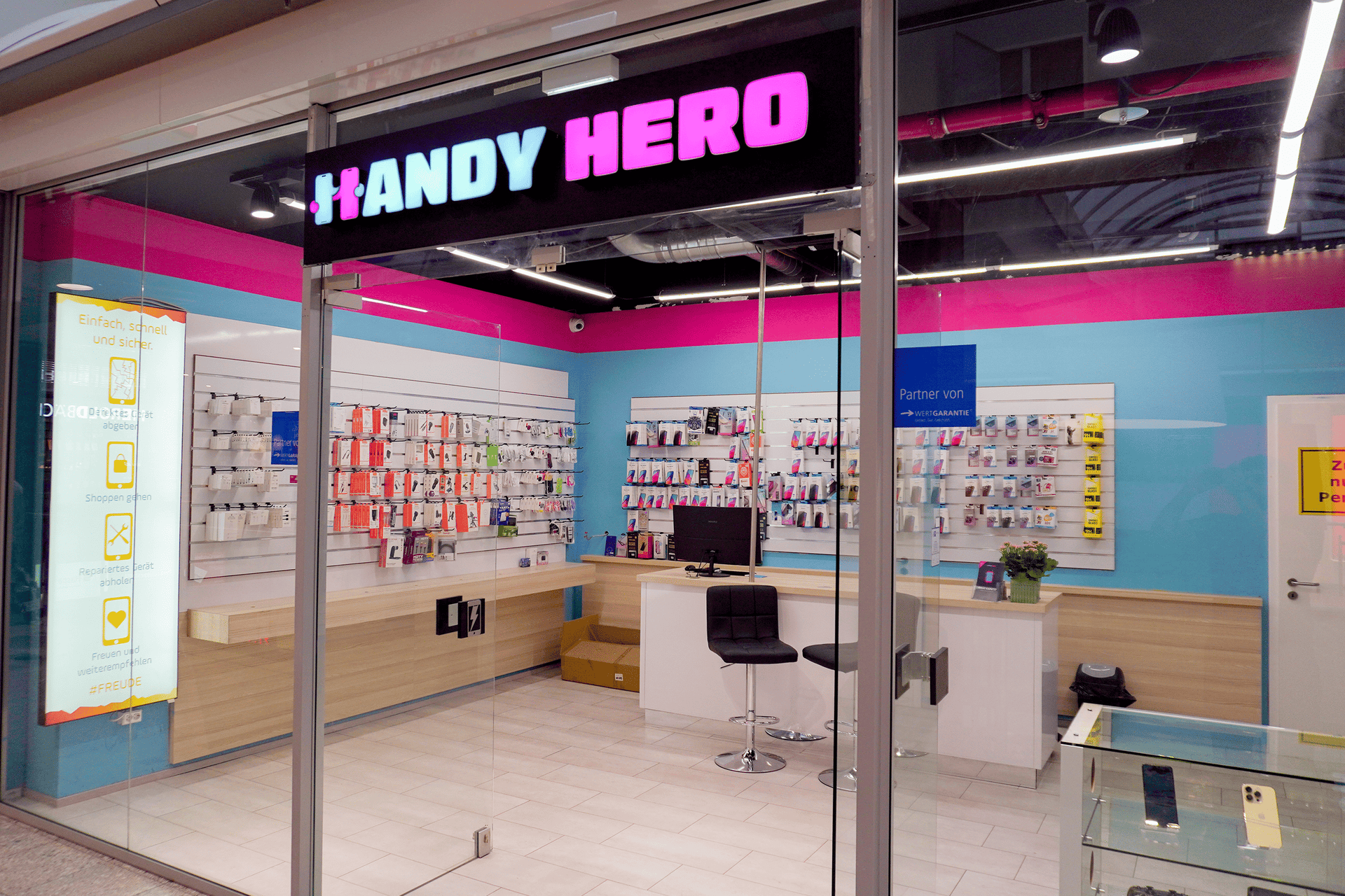 Glasfront der Handy Hero Filiale im Herold-Center mit Blick auf Zubehör und Beratungstheke