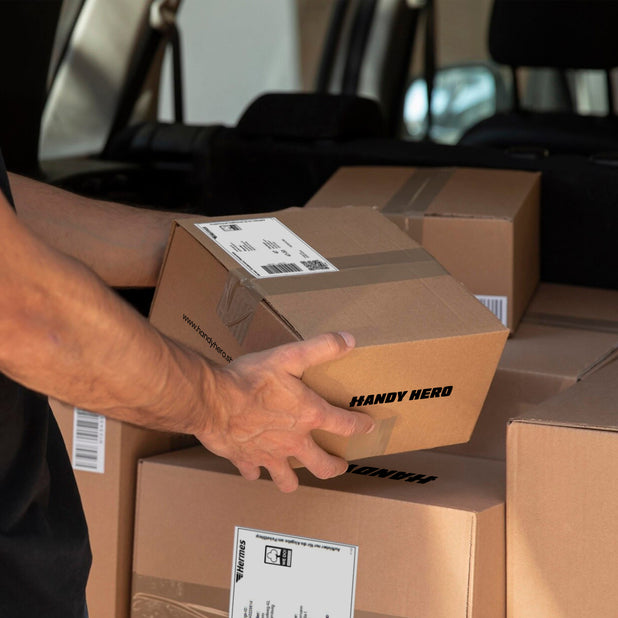 Nahaufnahme von Händen, die ein Smartphone in ein Versandpaket legen – Einsendeprozess